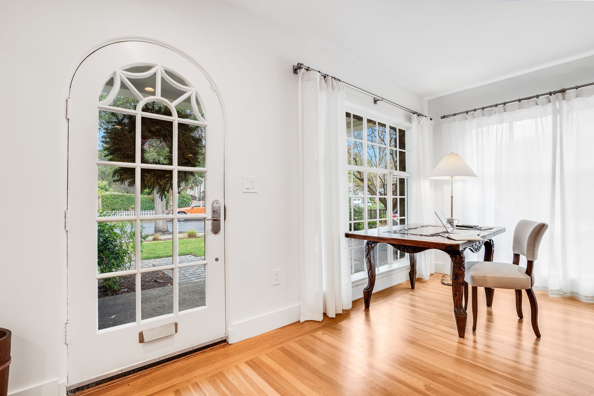 There is a desk and chair in the room with a large window.