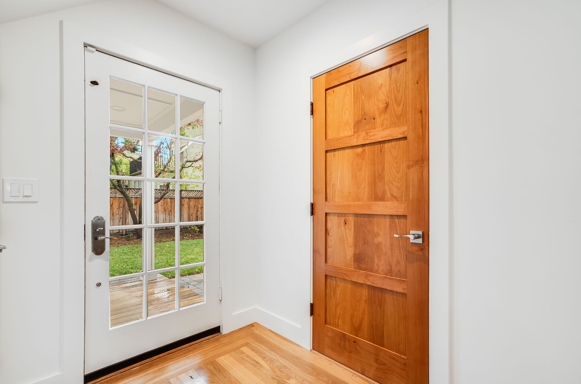 An empty room with a wooden door and a french door.