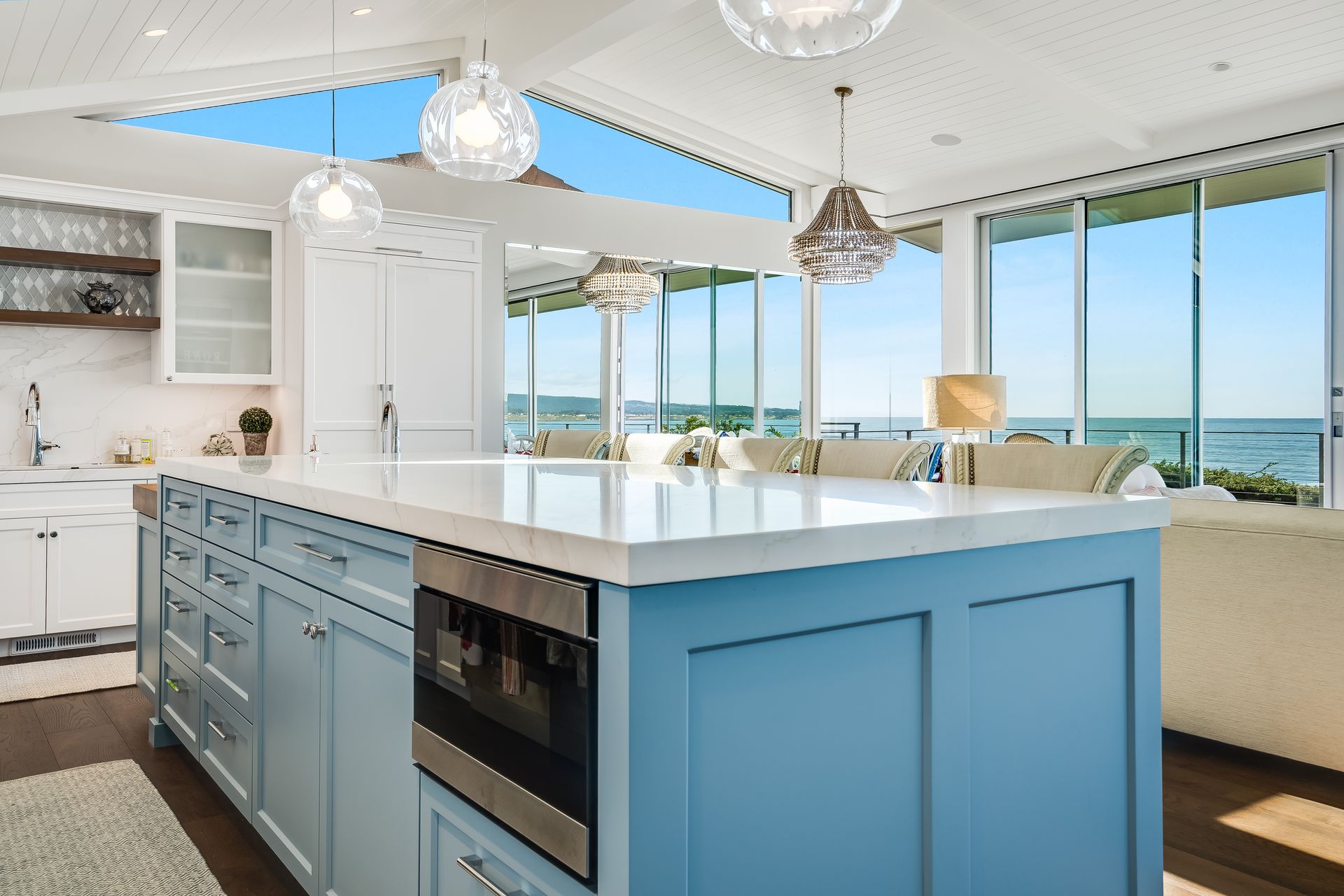 A kitchen with blue cabinets and a large island with a view of the ocean.