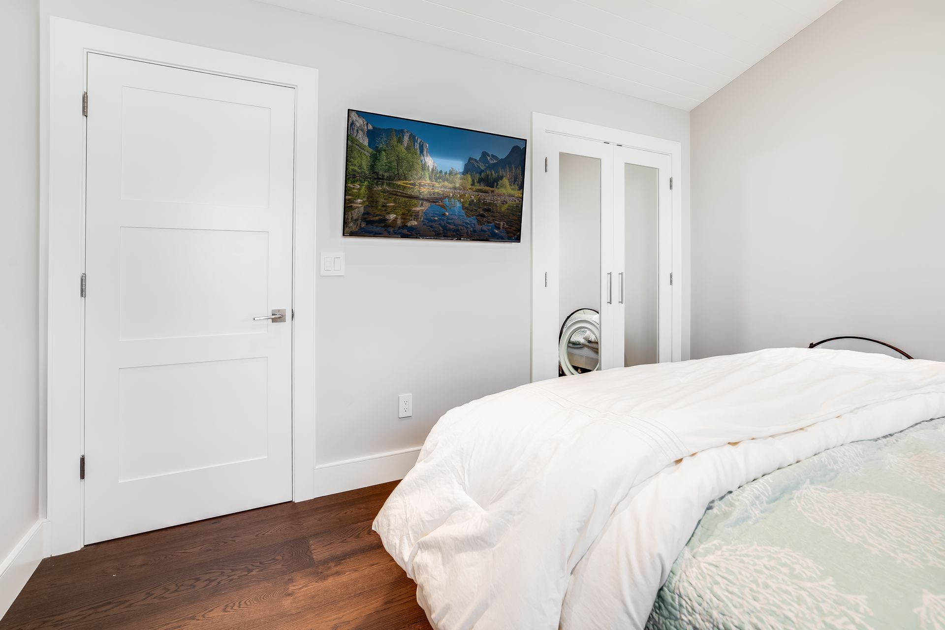 A bedroom with a bed and a television on the wall.
