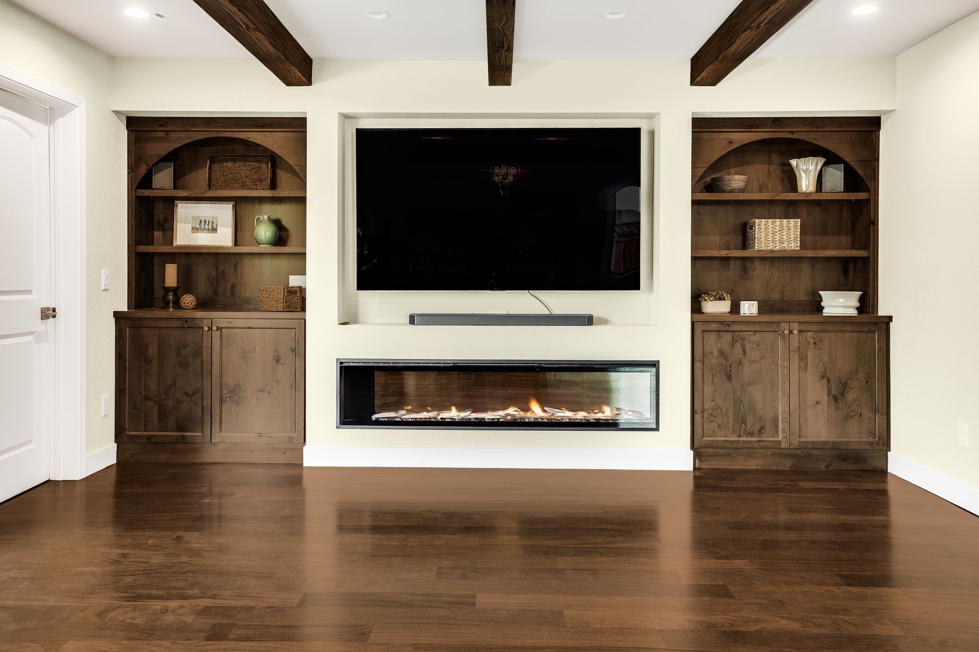 Living room with TV, fireplace, built-in shelves in wood. Exposed wooden beams. Hardwood floor.
