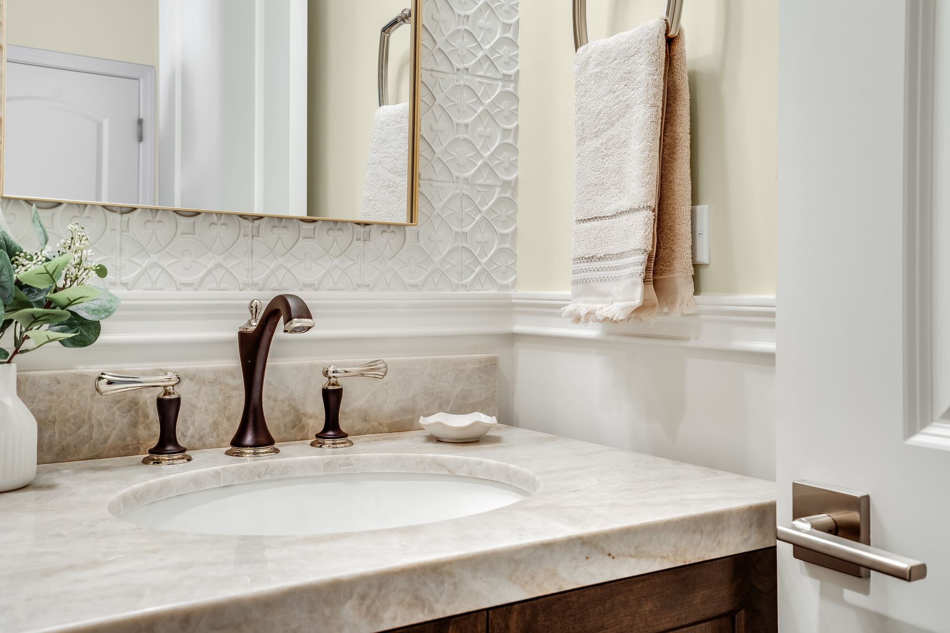 Bathroom sink with marble countertop, white basin, ornate faucet, and towel on rack.