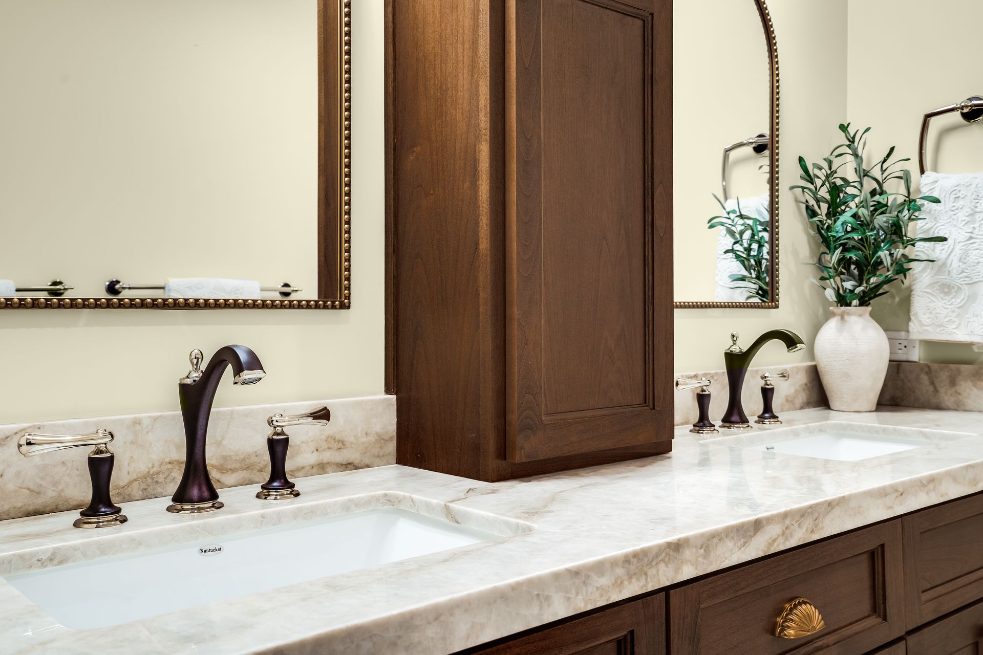 Bathroom with brown cabinets, marble countertop, and dark fixtures.