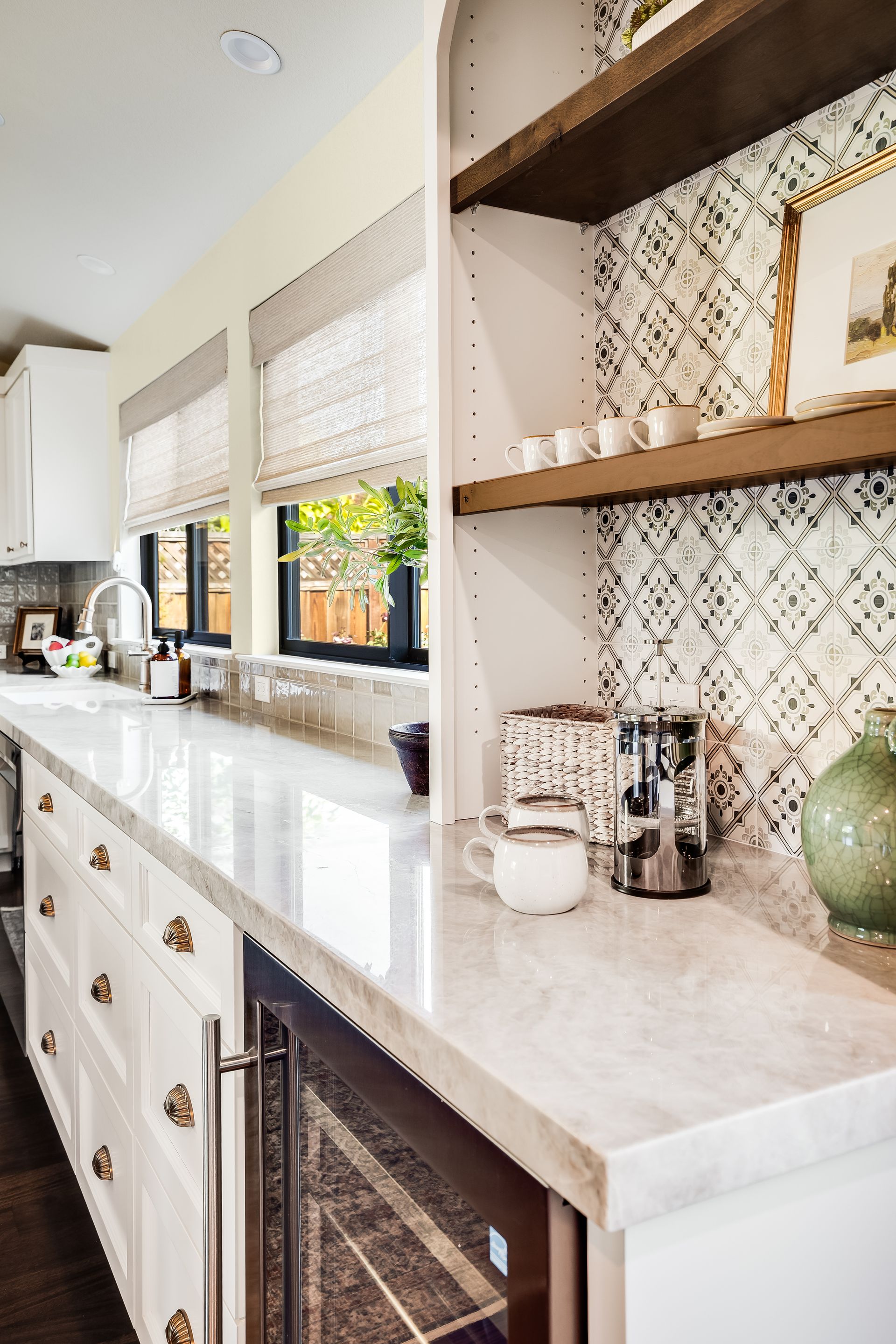 White kitchen with marble countertop, coffee station, and open shelving.