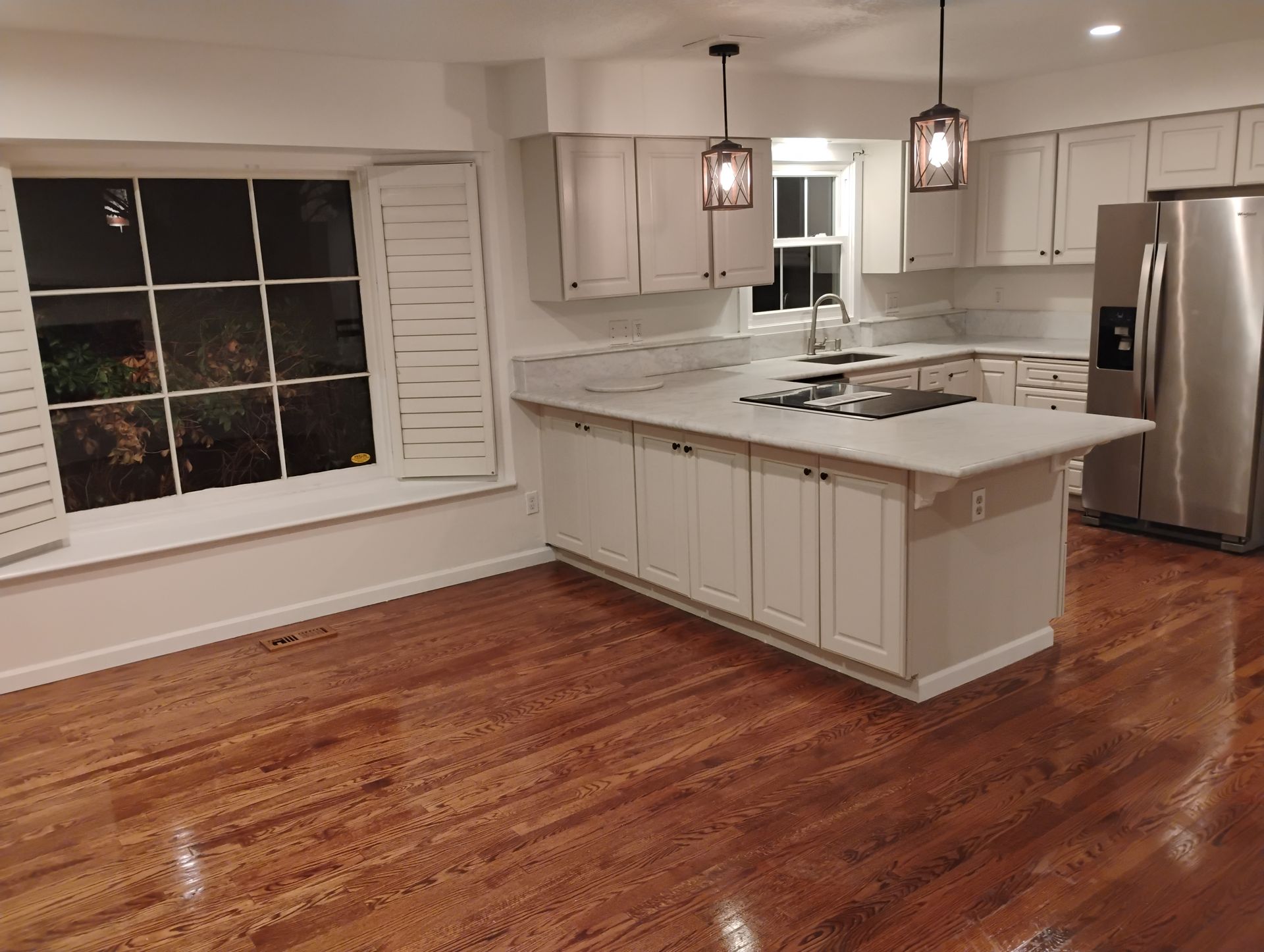Kitchen with light cabinets, white countertops, stainless steel appliances, and wood floors.