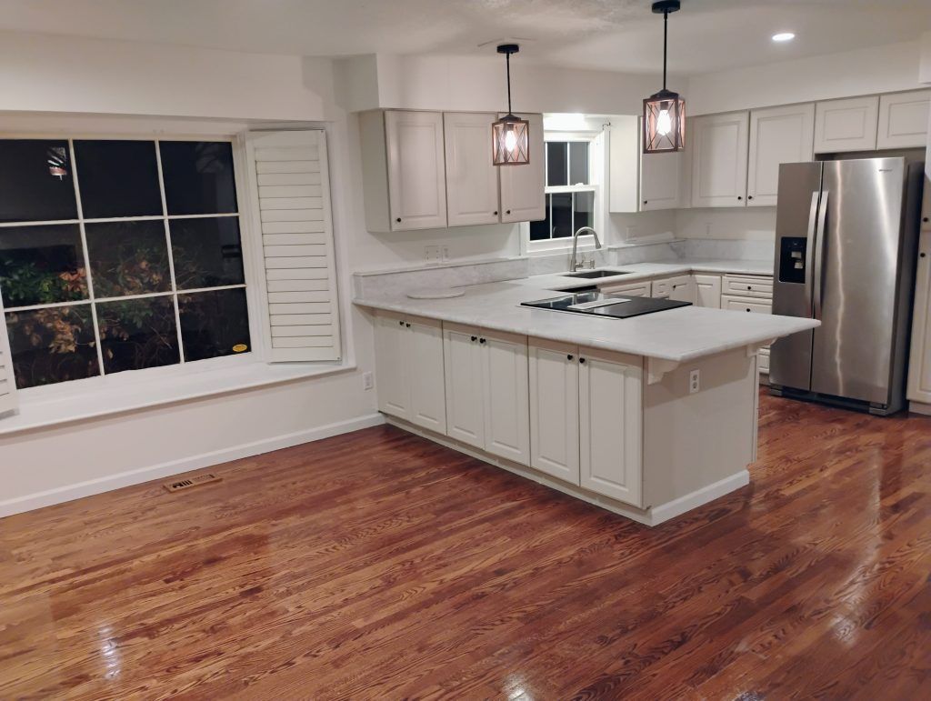 Kitchen with white cabinets, stainless steel appliances, and wood floors.