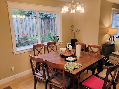 Dining room with wooden table, chairs, window, and chandelier.