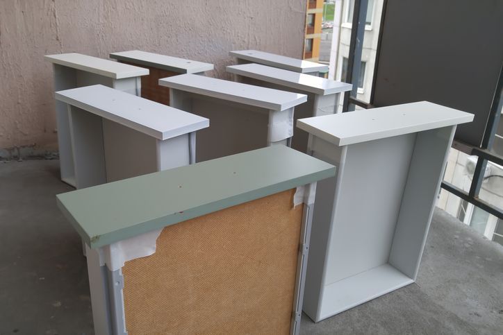 White painted drawer boxes, some with green tops, outdoors on a ledge.