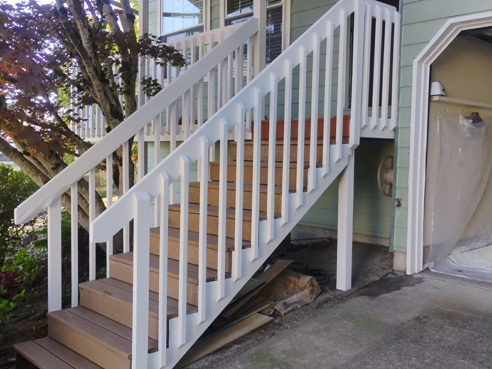 White painted wooden outdoor stairs leading up to a house with a garage.