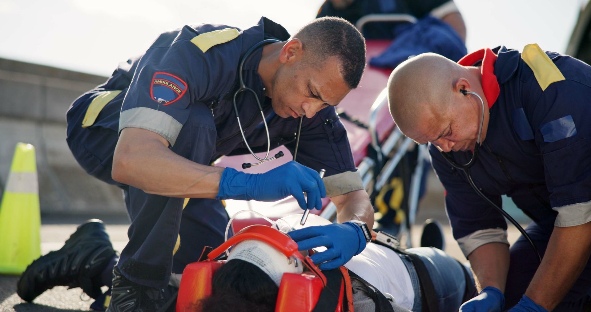 A group of paramedics are helping a person who is laying on the ground.
