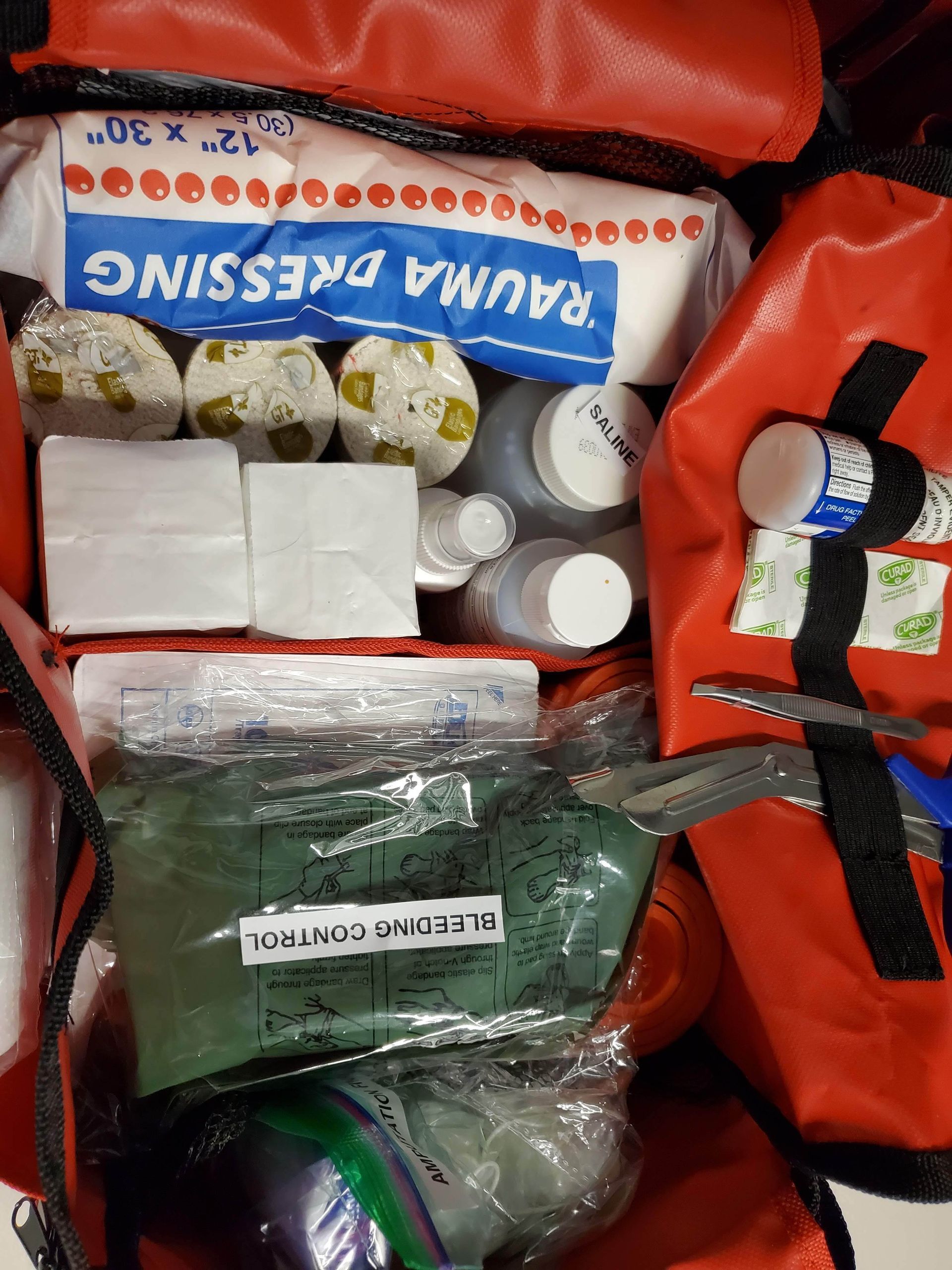 A red bag filled with first aid supplies including scissors