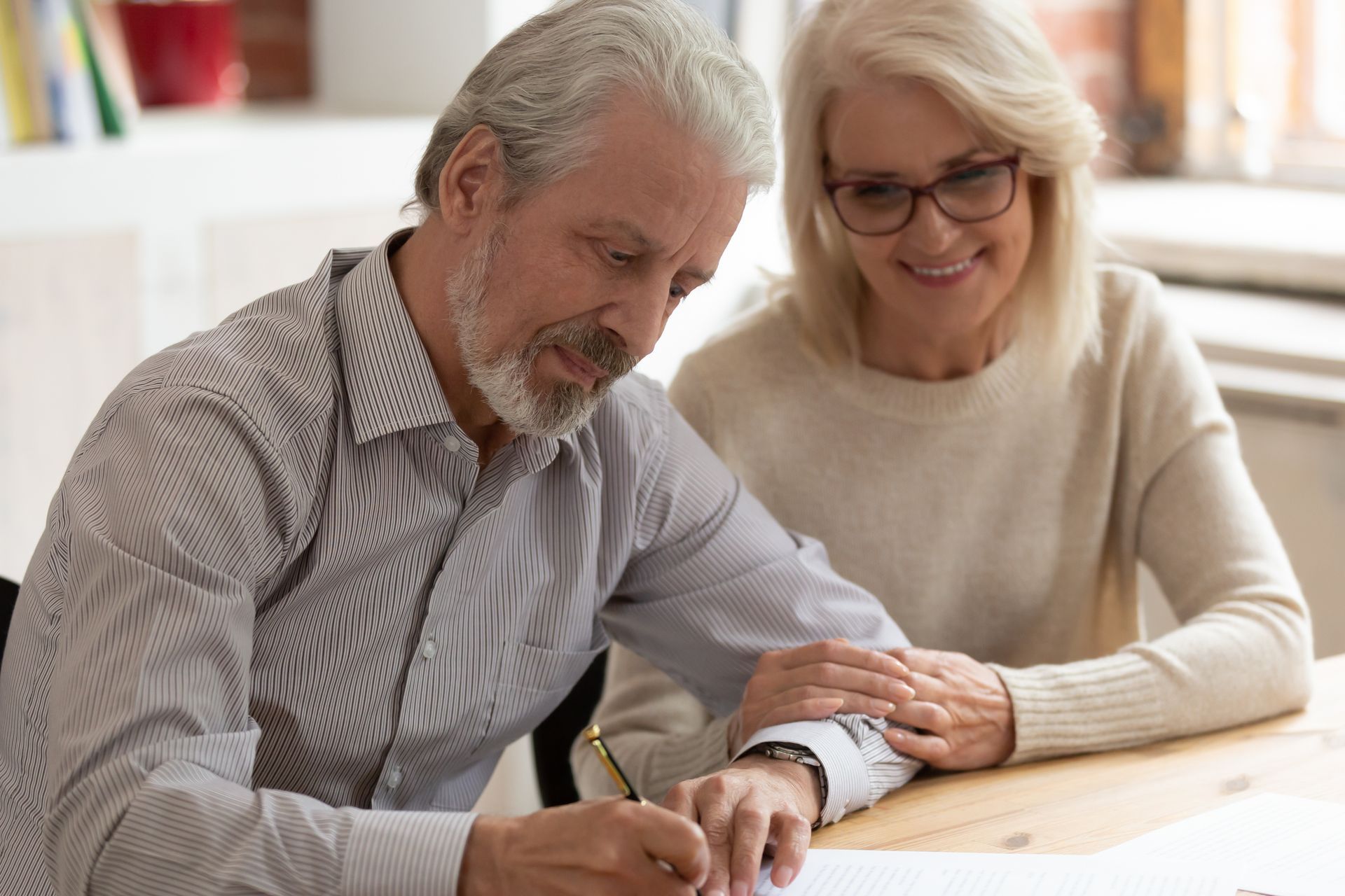 A man and a woman are sitting at a table signing a document.