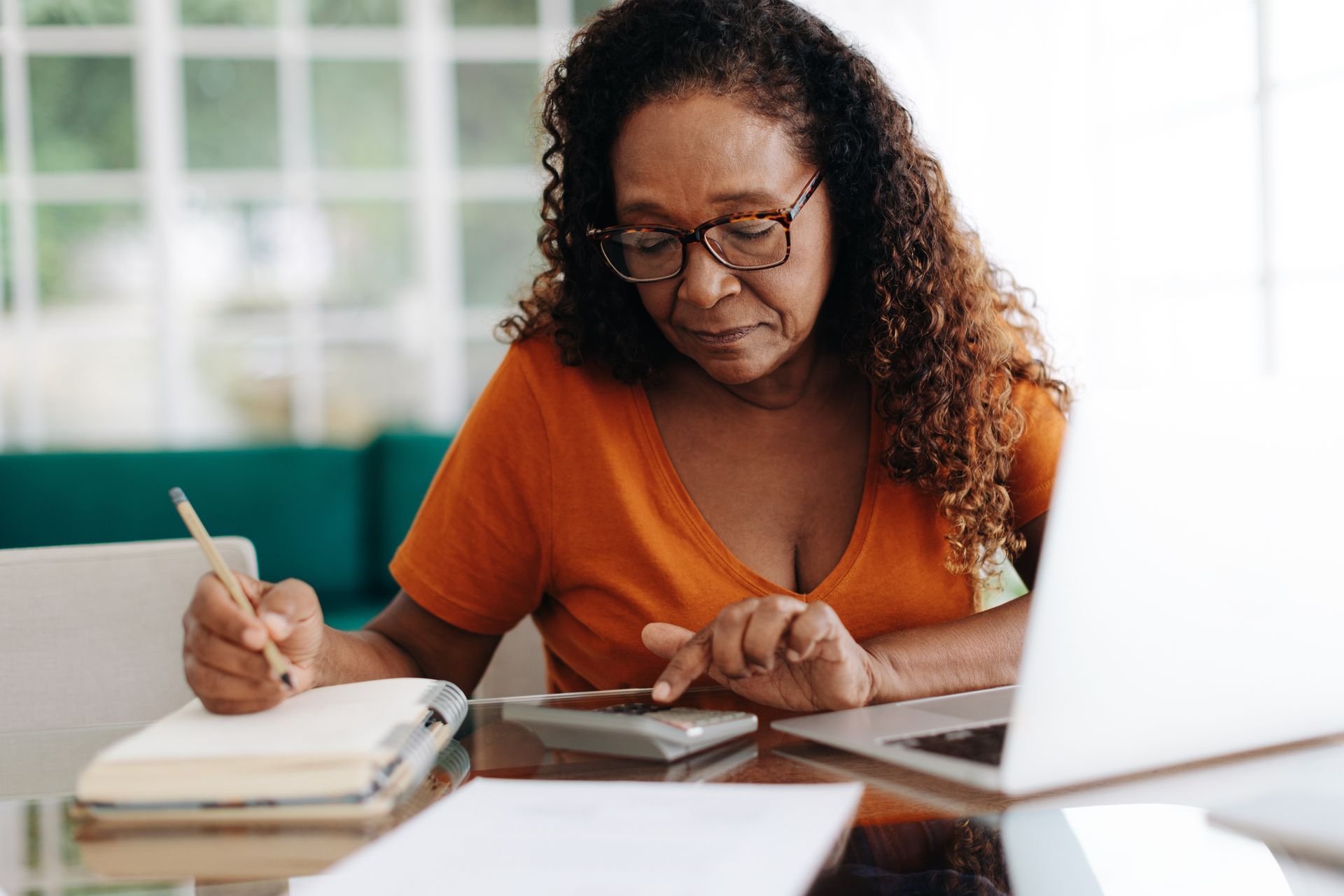 A woman is sitting at a table with a laptop and a calculator.