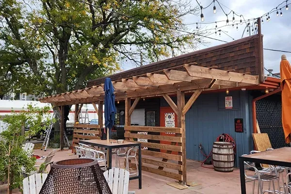 A restaurant with tables and chairs under a wooden pergola.