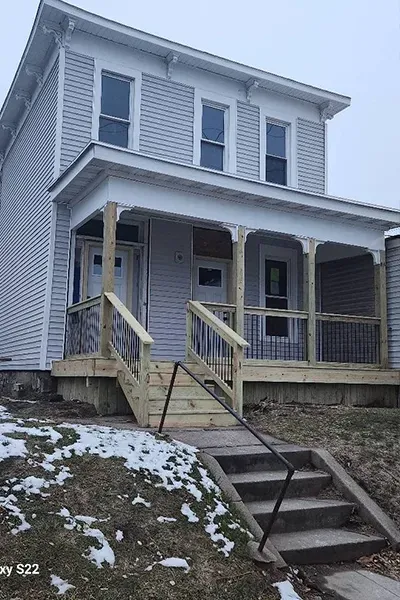 A white house with a wooden porch and stairs leading up to it.