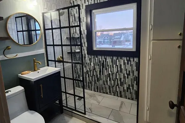 A bathroom with a toilet , sink , shower and mirror.