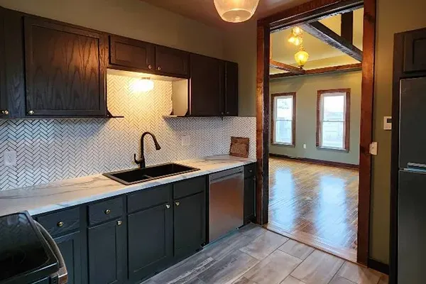 A kitchen with stainless steel appliances , a sink , and a refrigerator.