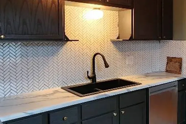 A kitchen with black cabinets and a black sink.