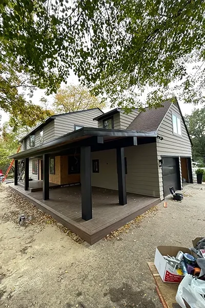 A house with a covered porch and a garage underneath it.