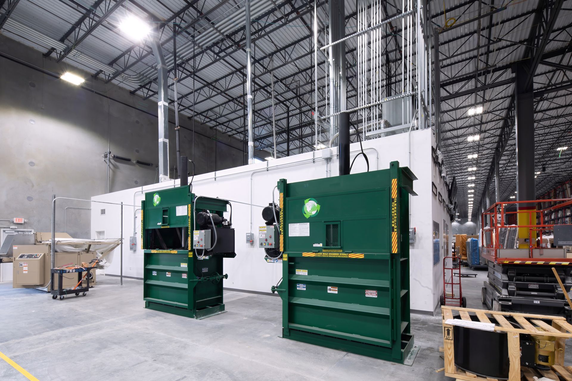 Two green industrial balers in a large warehouse.