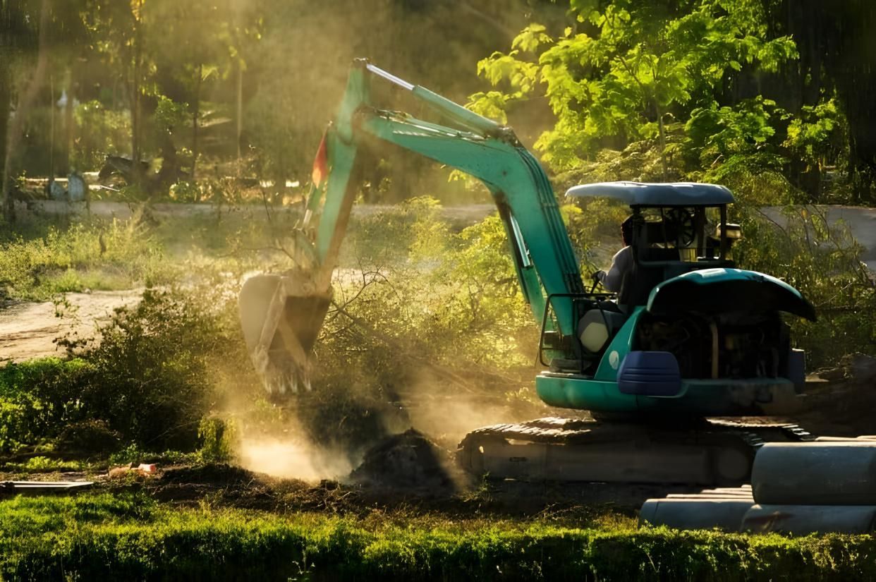 A Man is Driving an Excavator in a Field — Husky Demolition In Heatherbrae, NSW