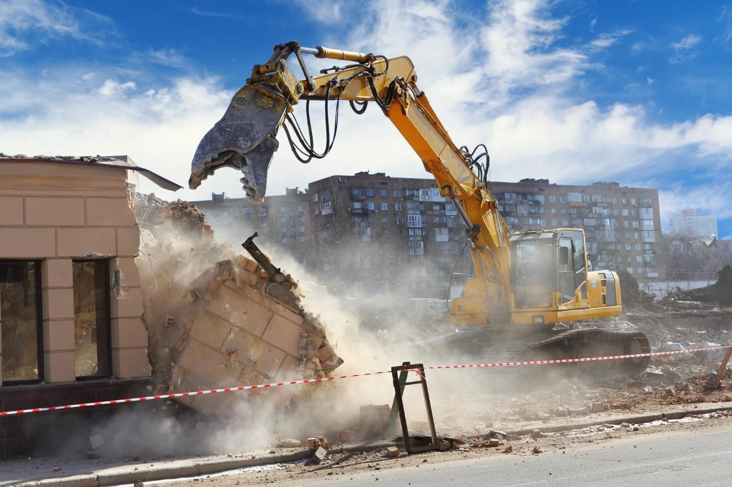 A Yellow Excavator is Demolishing a Building on a Construction Site — Husky Demolition In Taree, NSW