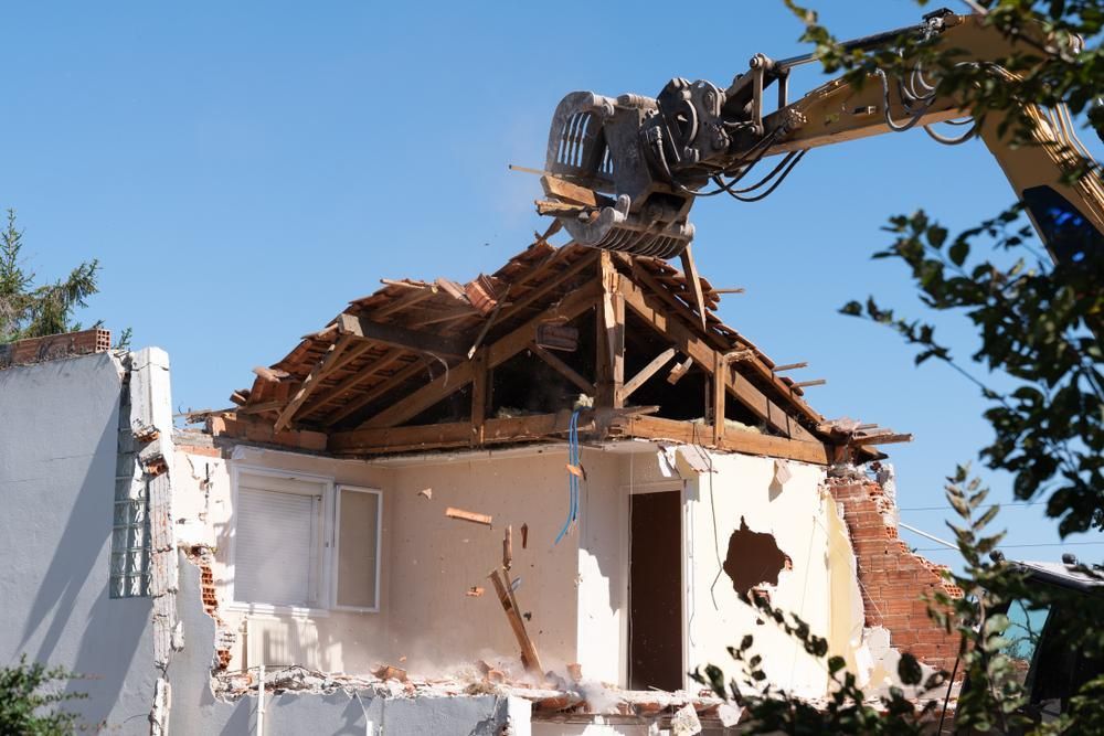 A House is Being Demolished by a Bulldozer — Husky Demolition In Port Stephens, NSW