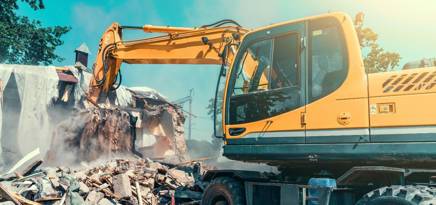 A Excavator is Demolishing a Building — Husky Demolition In Hamilton, NSW