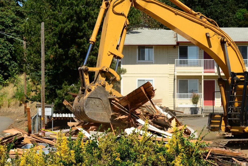 A Large Yellow Excavator is Demolishing a House — Husky Demolition In Taree, NSW