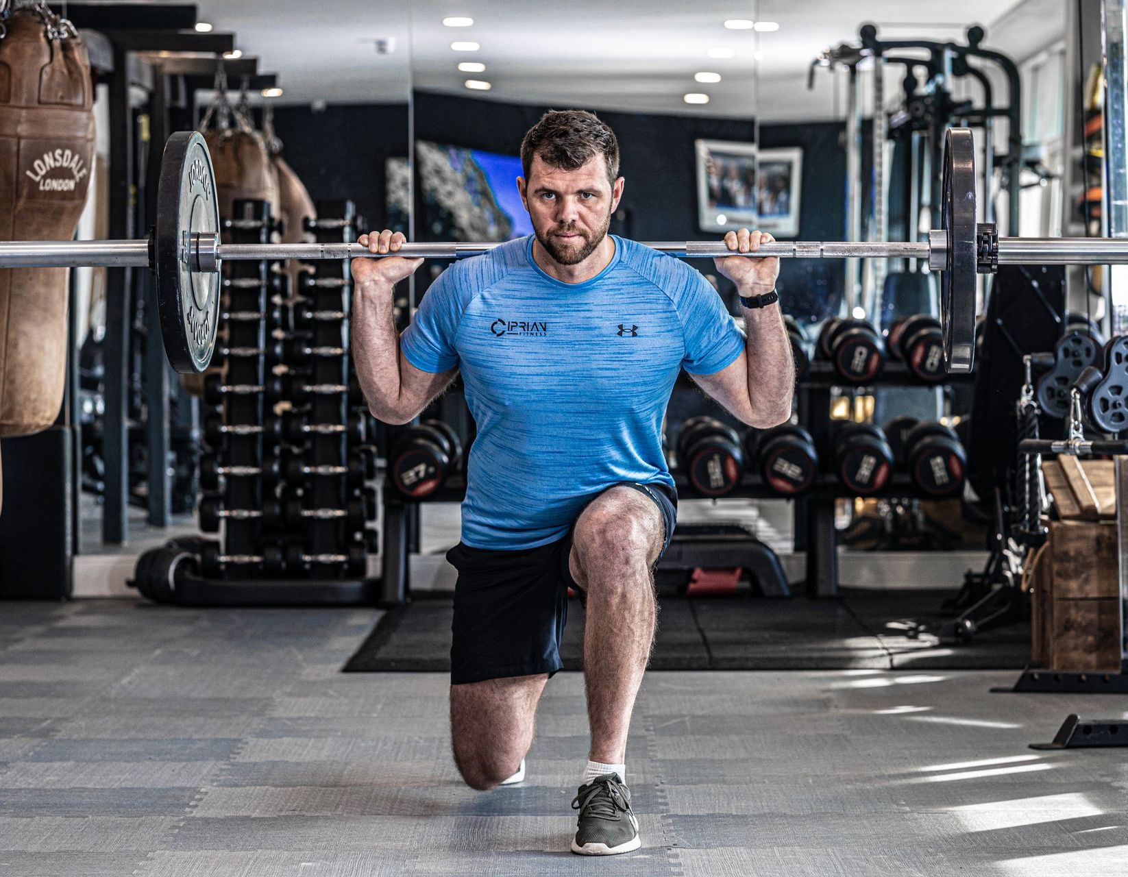 A man is squatting with a barbell in a gym.