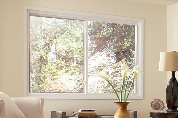 A living room with a large window and a vase of flowers on a table.