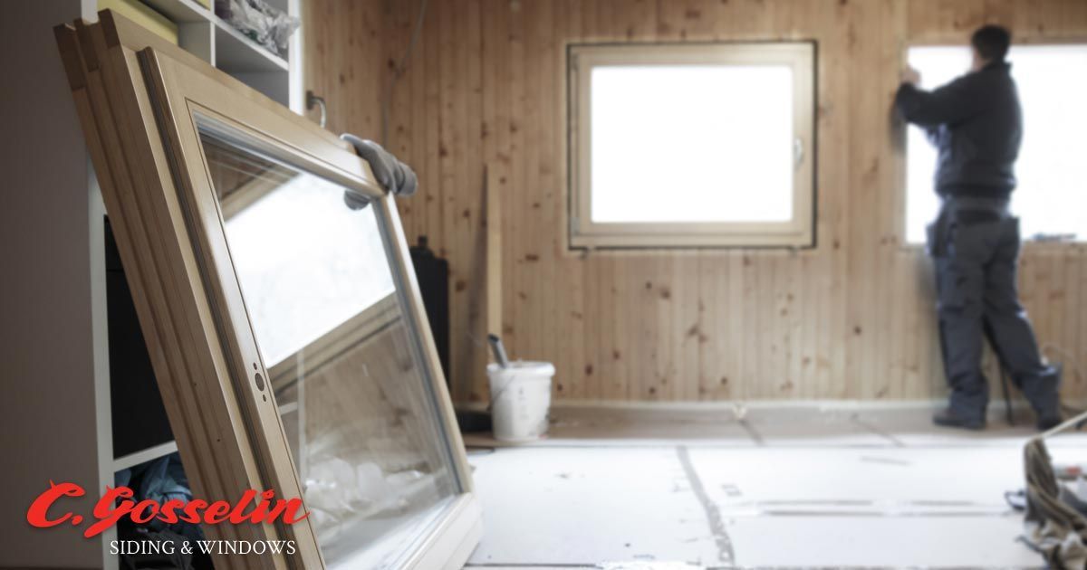 A man is installing a window in a wooden room.