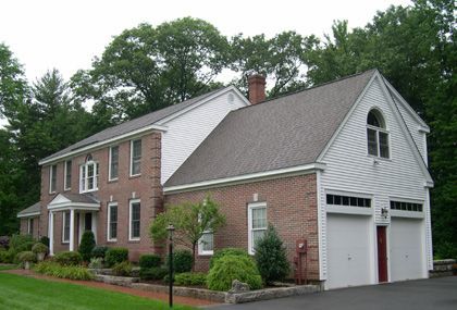 A large brick house with a white siding and a garage