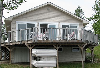 A house with a large deck and kayaks underneath it