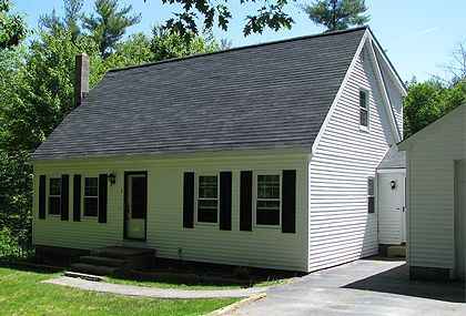 A white house with black shutters and a black roof