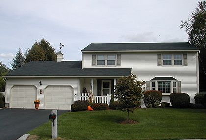 A white house with a black roof and two garage doors