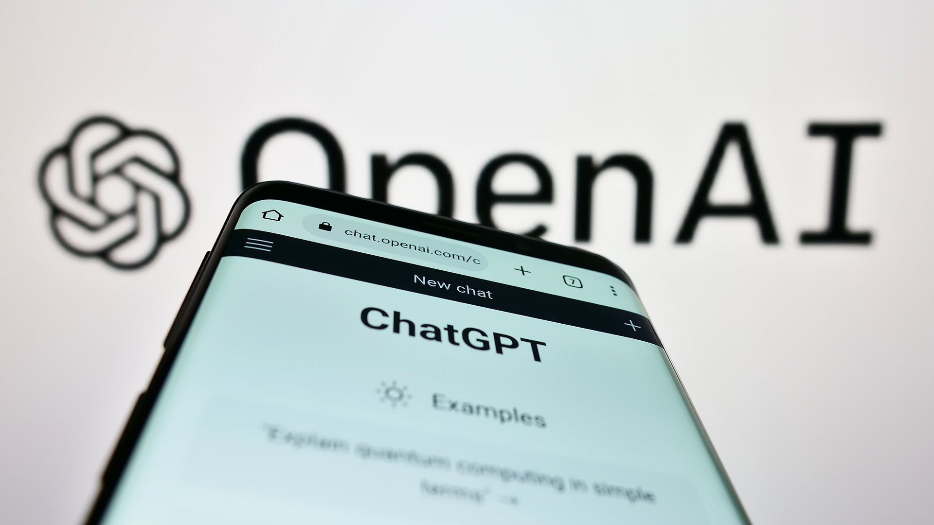 A cell phone is displayed in front of a sign that says openai