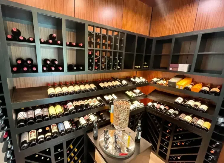 Wine cellar with shelves of bottled wine and a central display table in warm wood tones