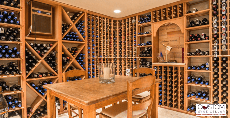 Wood-paneled wine cellar with floor-to-ceiling bottle racks, wooden table, and chairs under warm lighting