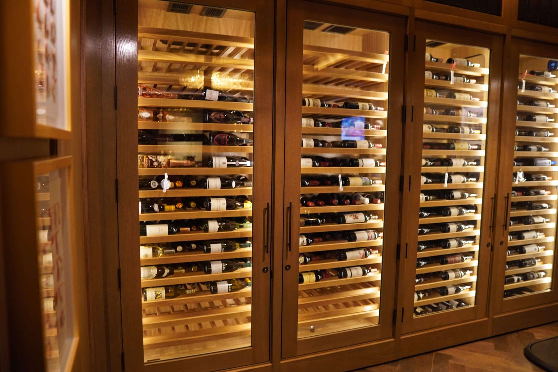 Wine bottles stored in wooden wine racks behind glass doors