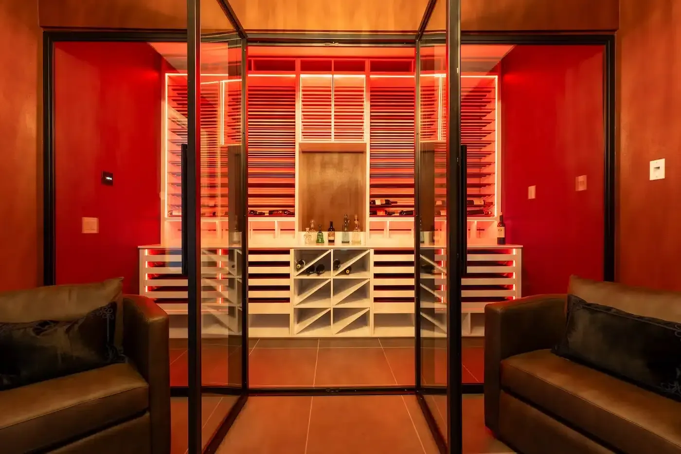 Red room with glass partition, white cabinets, and black sofas in a modern interior.