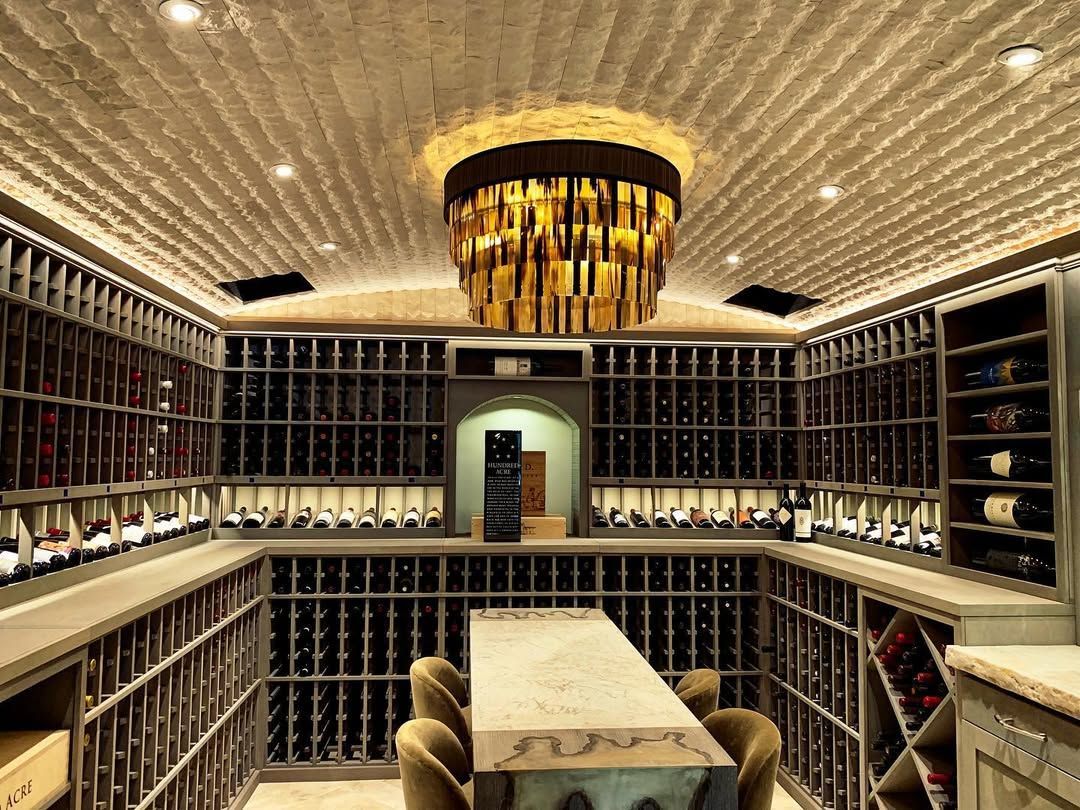Luxurious wine cellar with floor-to-ceiling racks, a long table, and a gold chandelier