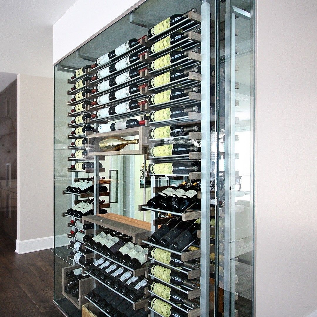 Wall-mounted glass wine rack filled with bottles in a modern room