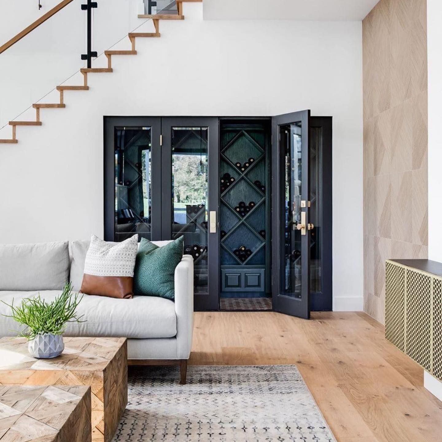 Modern living room with white sofa, staircase, dark blue front door, and wood floors