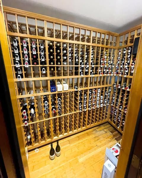 Corner wine cellar with wooden racks filled with bottles and a pair of shoes on the floor