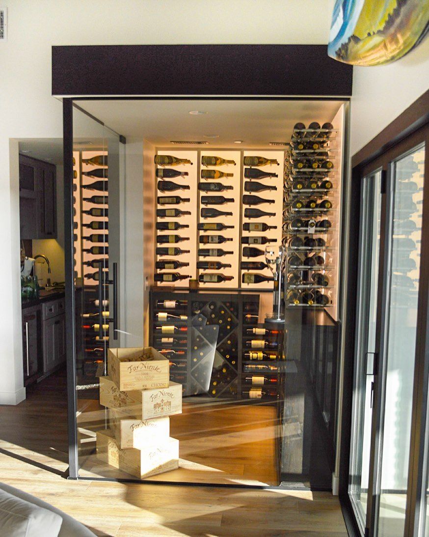 Wine display room with glass doors and wall-mounted racks filled with bottles.