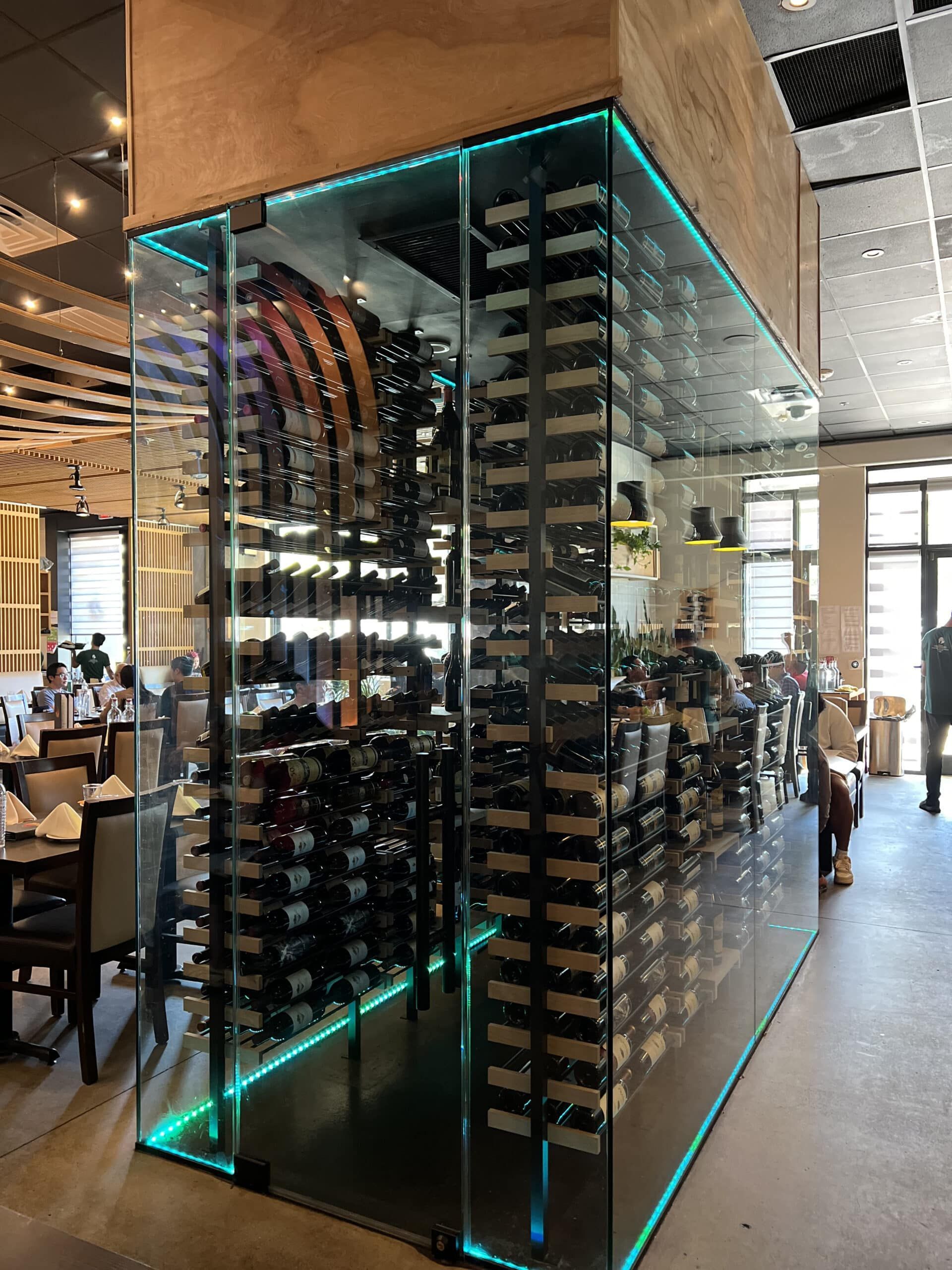 Glass wine storage display with turquoise LED trim in a restaurant interior