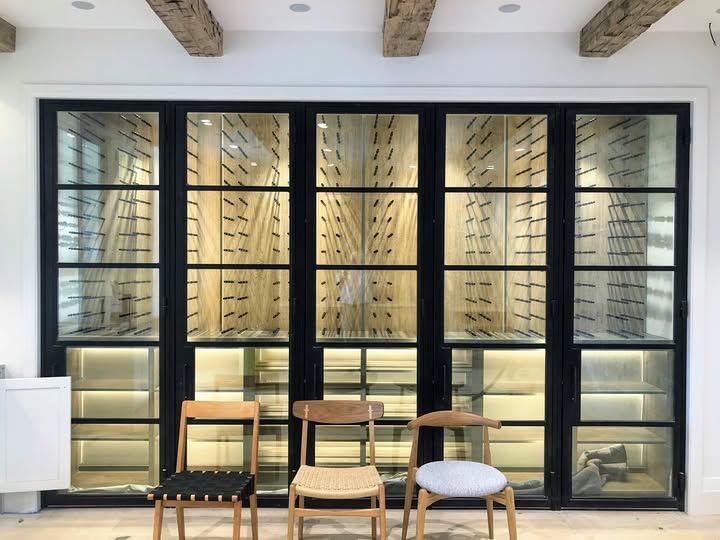 Modern storefront with black-framed windows and three chairs on a sidewalk patio