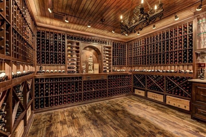 Wood-paneled wine cellar with floor-to-ceiling bottle racks and a wooden ceiling