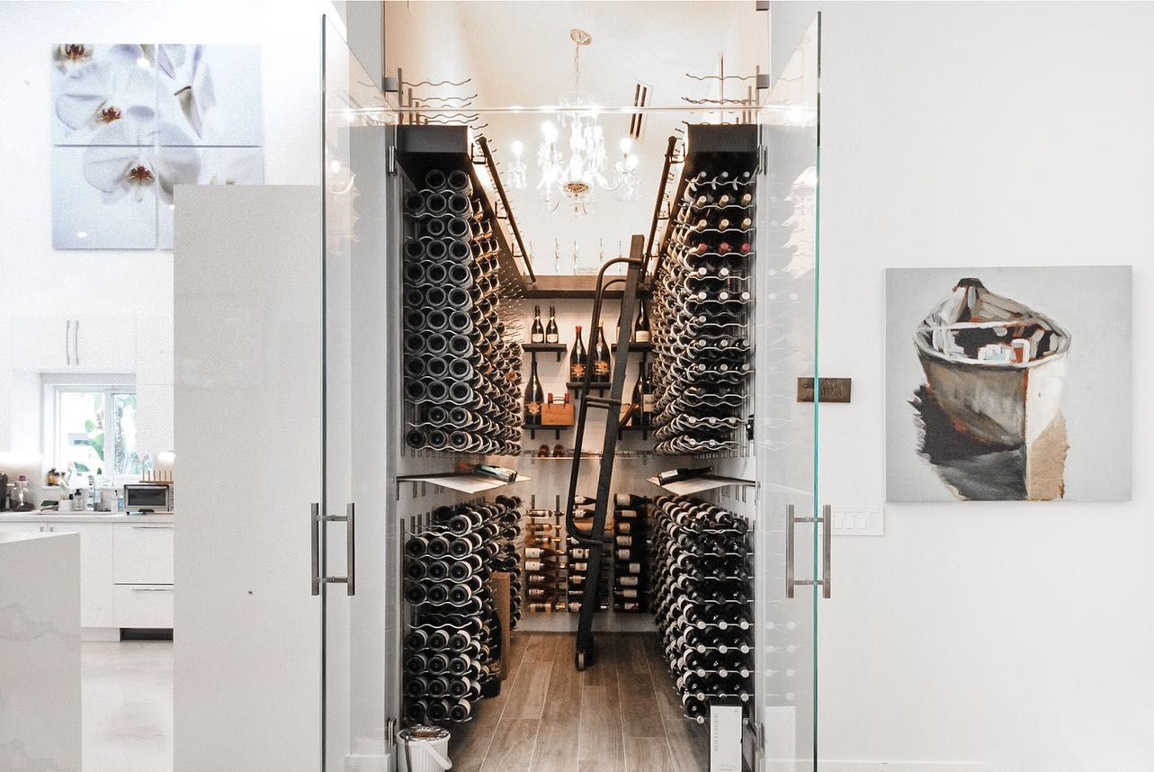 Glass-door wine cellar lined with bottles in a bright modern interior